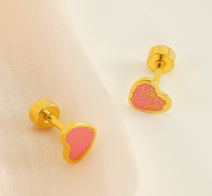 Close-up of pink enamel heart earrings with yellow polka dots on silk background