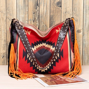 Detailed close-up of woven bohemian tote bag featuring fringe tassels and leather handles