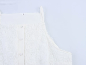 Detailed macro shot of white camisole top with textured 3D floral pattern and buttons