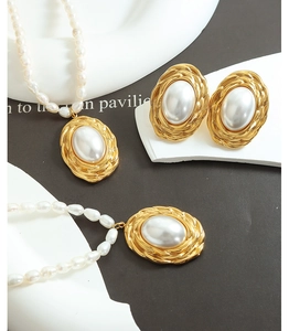 Detailed close-up of gold-plated embossed earrings and necklace with freshwater pearls