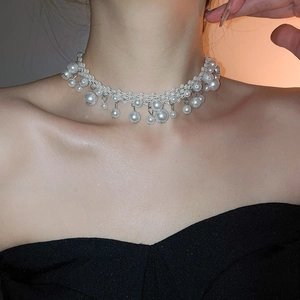 Detail of French vintage pearl choker necklace with intricate tassel on neck