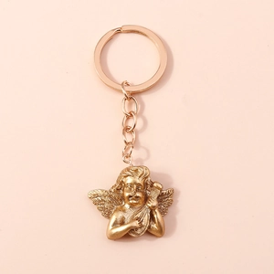 Detail of vintage gold angel keychain featuring an embossed cherub holding an instrument