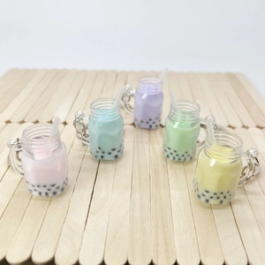 Five colorful bubble tea keychains in pastel colors arranged on a rustic wooden background