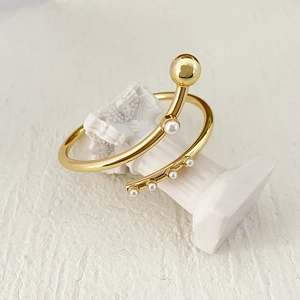 Adjustable gold plated knot cuff bracelet with white pearls on a classical pedestal