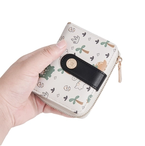Detail of white bifold wallet featuring cute dinosaur print and gold zipper hardware
