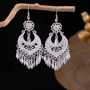 Detail view of silver bohemian tassel earrings hanging on a dry wooden branch branch