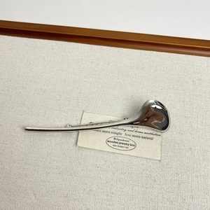 Macro detail of the smooth silver streamline metal brooch with a polished finish