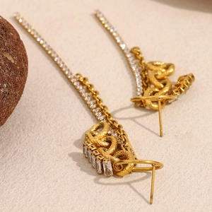 Détail des boucles d'oreilles serpent dorées avec glands en zircon et fermoir aiguille