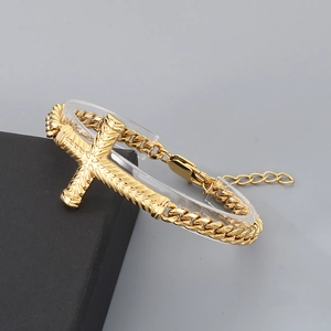 Détail d'un bracelet gourmette doré avec pendentif croix à motifs sur support acrylique