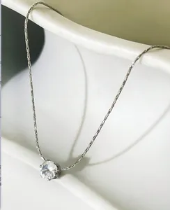 Detailed close-up of a silver necklace featuring a round sparkling zircon pendant