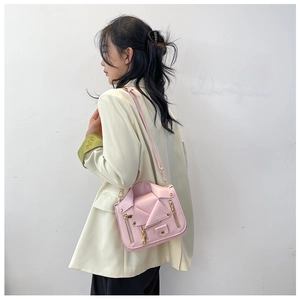Detailed side view of light pink moto jacket crossbody bag with gold rivet accents