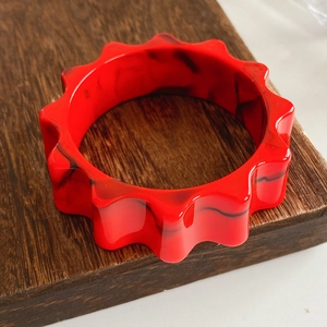 Detail of red and black marble texture on wide resin wavy gear bangle bracelet