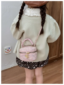 Detail of pink sequin crossbody bag with chain strap and flower charm on child model