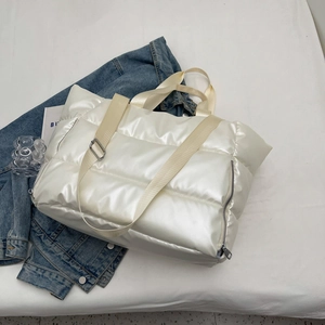 Detail of white quilted gym bag with glossy finish and woven strap on denim jacket