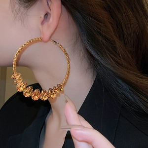 Detailed view of large gold hoop earrings with faceted amber crystals on model