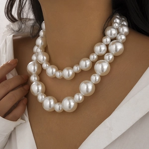 Detailed view of layered faux pearl necklace with sparkling heart charm on a model