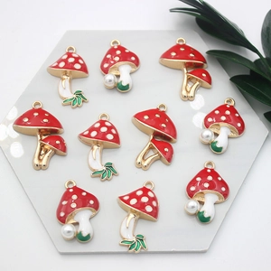 Detailed view of red mushroom enamel charms with gold edges and pearl accents for DIY jewelry