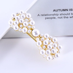Close-up of golden bow hair clip with white pearls and sparkling rhinestone details