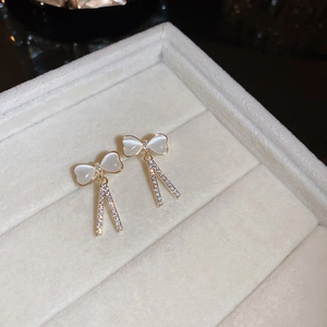 Détail des boucles d'oreilles nœud plaquées or avec pierres œil-de-chat et glands