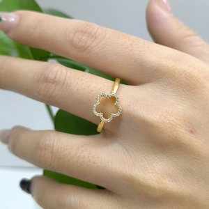 Detailed view of a gold five-petal flower ring with sparkling zircon stones on finger