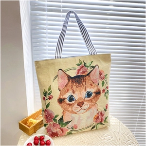 Detail of canvas tote bag with floral cat embroidery and blue striped strap