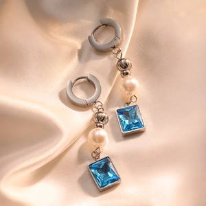 Silver geometric earrings with white pearl and square blue gemstone on satin background