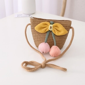 Straw shoulder bag for kids with yellow bow and pink cherry charms on white desk