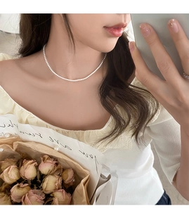 Détail d'un collier de perles blanches délicat porté avec une esthétique élégante