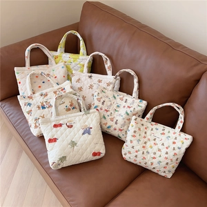 Detailed view of quilted cotton tote bags with cute bear and rabbit prints on a sofa