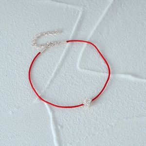 Detail of red braided rope bracelet with silver clover pendant and adjustable clasp