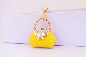 Detail of yellow handbag keychain with sparkling rhinestones and white bow accent