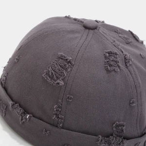 Close-up of distressed dark grey cotton docker cap with vintage frayed hole details