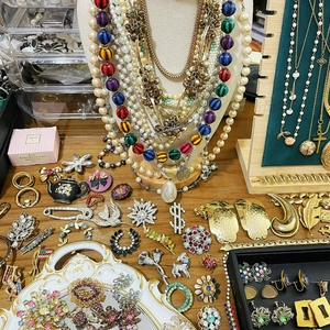 Vintage gold-tone jewelry collection with faux pearls and rhinestones on a wooden surface