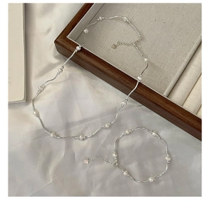 Detail of silver wavy chain and white freshwater pearl necklace with heart charm