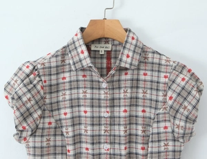 Detail of red and black plaid short sleeve shirt with puff sleeves and heart patterns