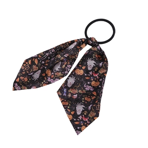 Close-up of Halloween hair scrunchie with pumpkin, ghost, and bat patterns on black ribbon