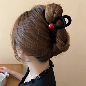 Elegant matte black shark hair claw with red velvet bead detail shown on model