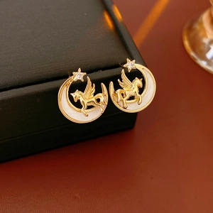 Detailed close-up of golden crescent moon earrings with unicorn and star gemstone