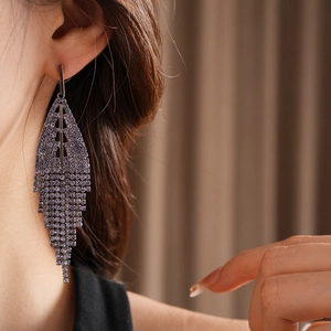 Close-up of dangling silver tassel earrings with rows of lavender cubic zirconia