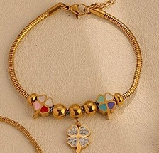 Detailed close-up of golden snake chain bracelet featuring multi-color clover charms and beads