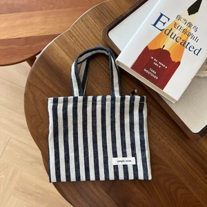 Close-up of a blue and white striped canvas tote bag with a Simple Wish woven label