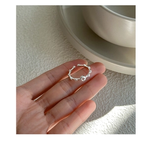 Detailed view of silver open ring featuring hollow cross and clover design on finger