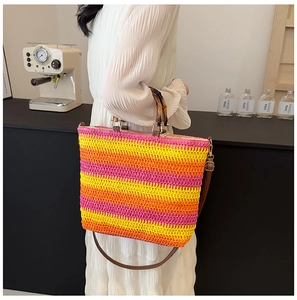 Detail of woven straw tote bag featuring colorful stripes and bamboo style handles