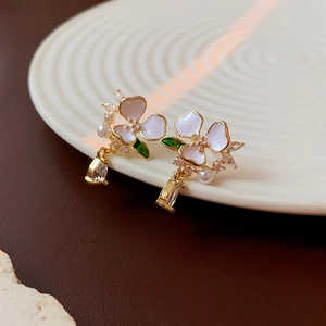 Detail of floral earrings with gold plating, white enamel petals and pearl charms