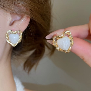 Detailed close-up of gold-plated heart stud earring featuring a white resin center stone