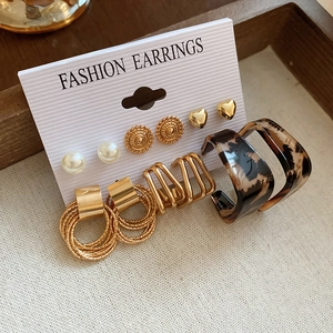 Detailed set of butterfly pearl and heart stud earrings on a fashion display card