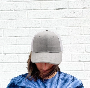 Grey and white flat brim trucker hat with breathable mesh back worn by a model