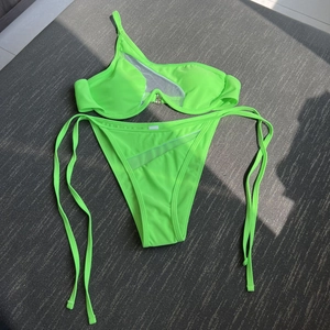 Detailed flat lay of a neon green bikini with mesh panels and asymmetric cut-out design