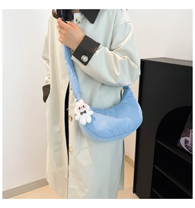Detail of light blue dumpling bag with a cute rabbit plush charm on a beige trench coat