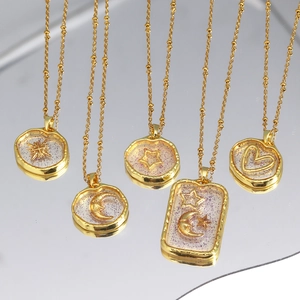 Golden sun moon and star heart pendant necklaces with resin glitter on reflective surface